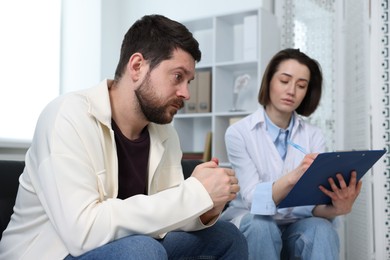 Photo of Alcoholic man having appointment with healthcare specialist in clinic. Addiction treatment