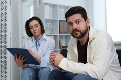 Photo of Alcoholic man having appointment with healthcare specialist in clinic. Addiction treatment