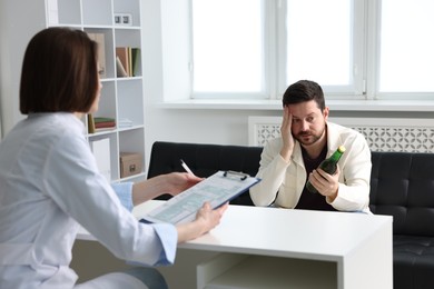 Photo of Alcoholic man having appointment with healthcare specialist in clinic. Addiction treatment