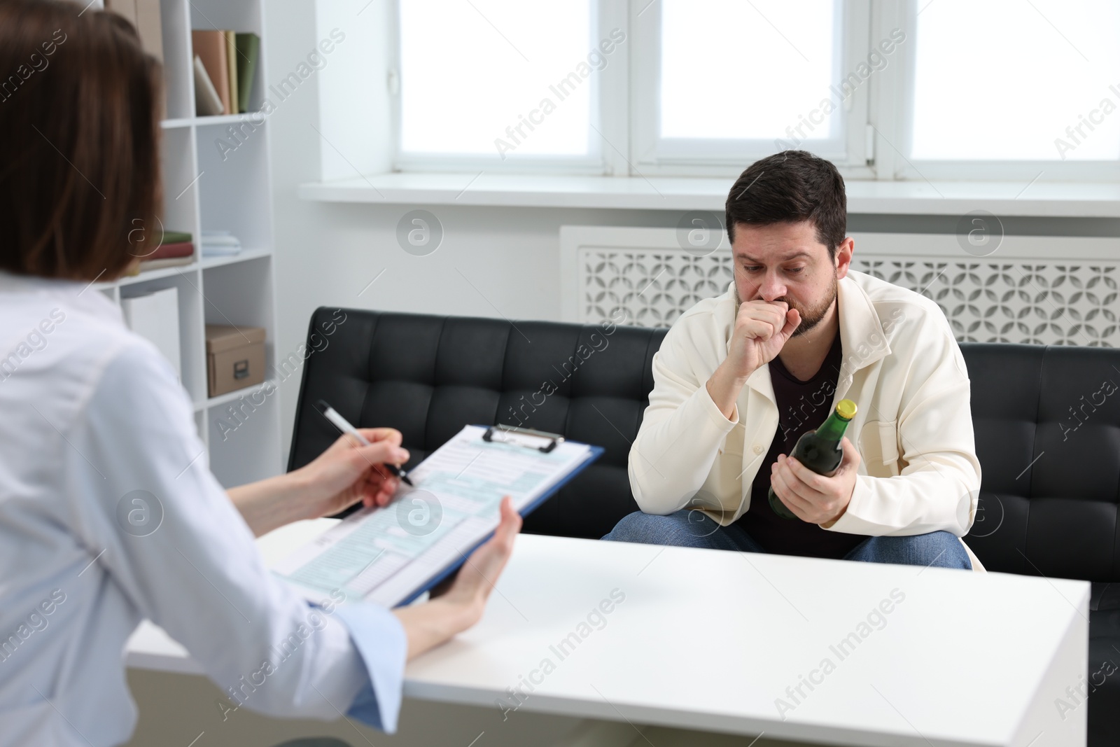 Photo of Alcoholic man having appointment with healthcare specialist in clinic. Addiction treatment