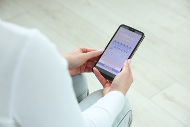 Photo of Menstruation. Woman using period calendar application on smartphone indoors, closeup