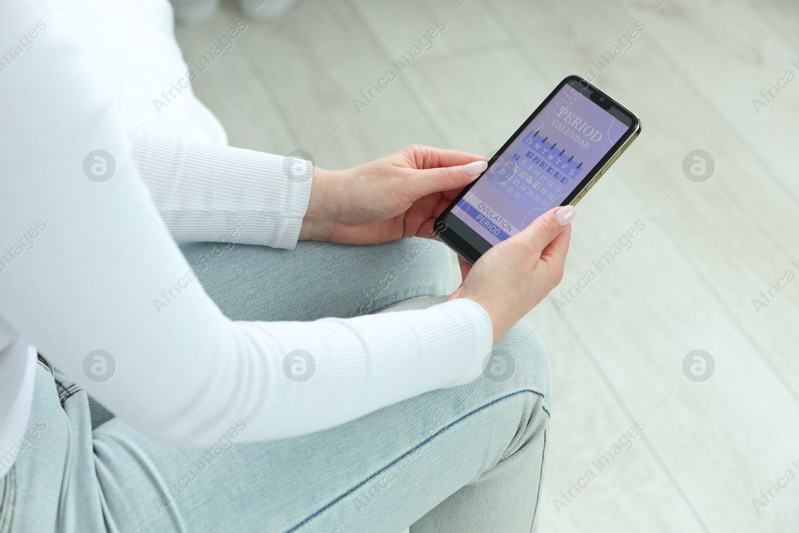 Photo of Menstruation. Woman using period calendar application on smartphone indoors, closeup