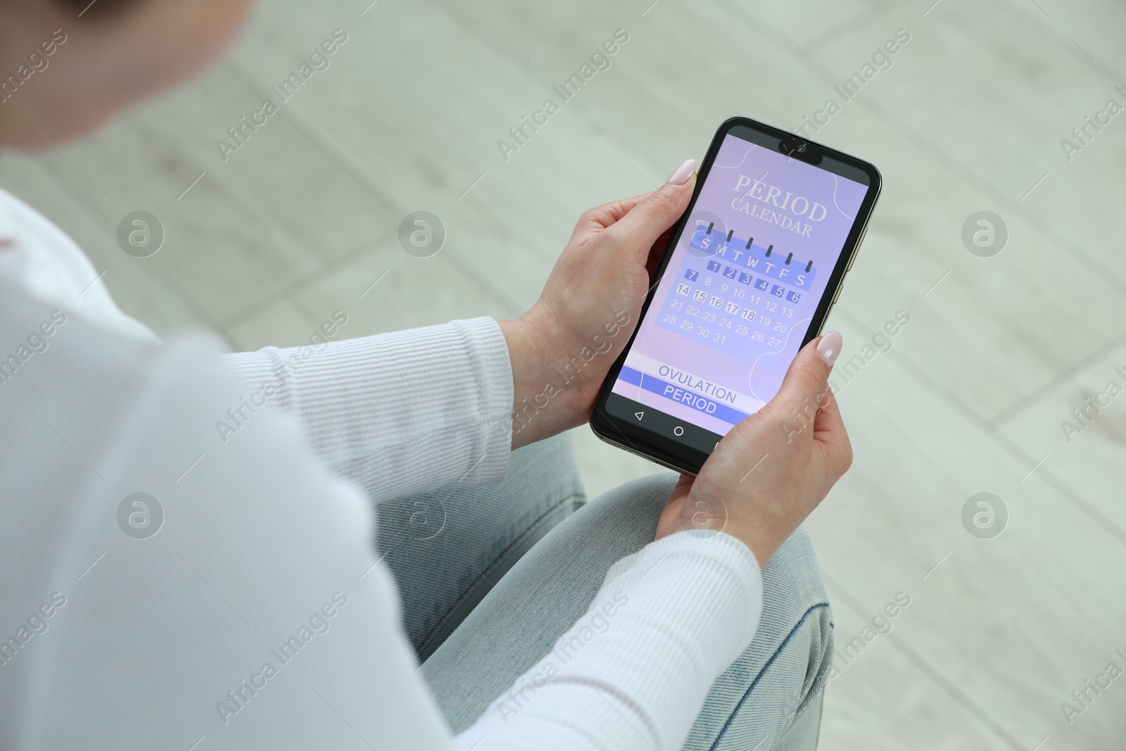 Photo of Menstruation. Woman using period calendar application on smartphone indoors, closeup