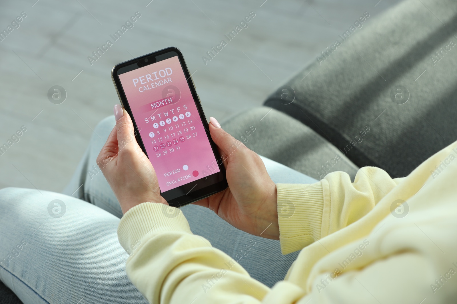 Photo of Menstruation. Woman using period calendar application on smartphone indoors, closeup