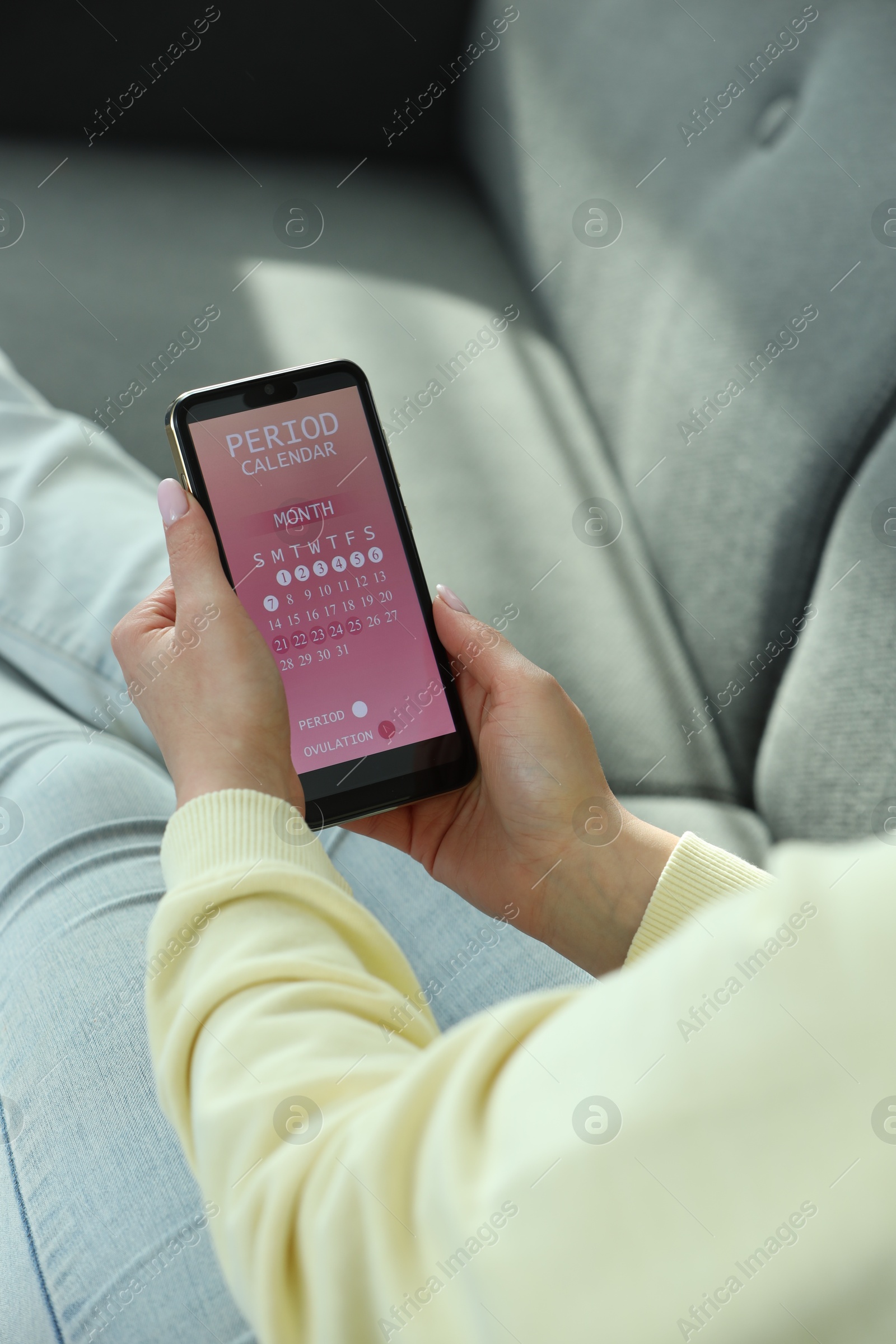 Photo of Menstruation. Woman using period calendar application on smartphone indoors, closeup