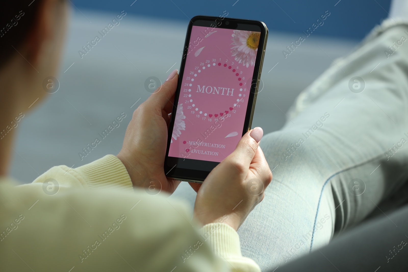 Photo of Menstruation. Woman using period calendar application on smartphone indoors, closeup