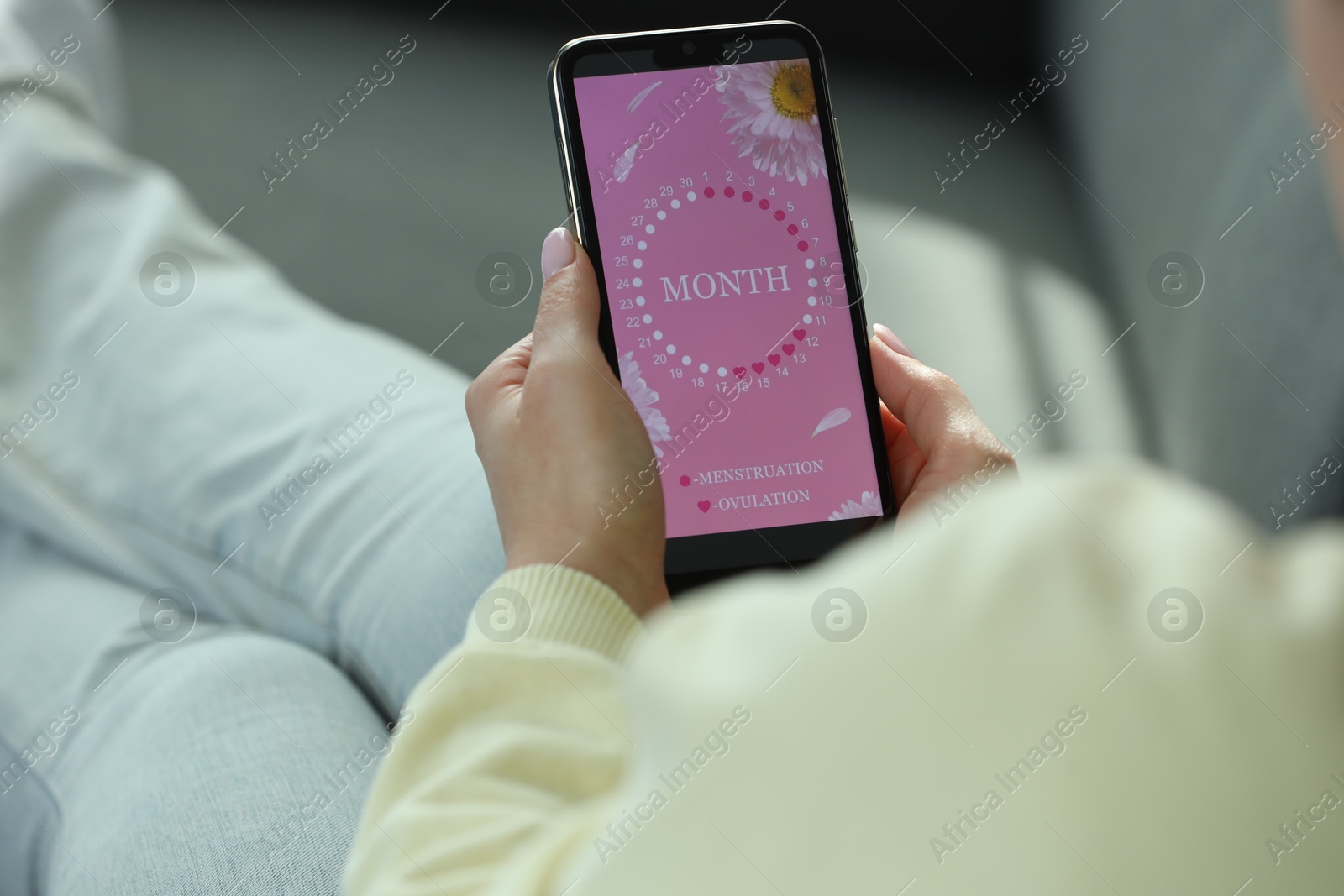 Photo of Menstruation. Woman using period calendar application on smartphone indoors, closeup