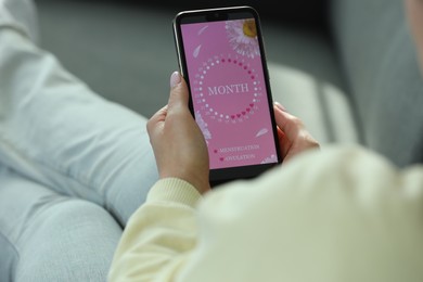 Photo of Menstruation. Woman using period calendar application on smartphone indoors, closeup