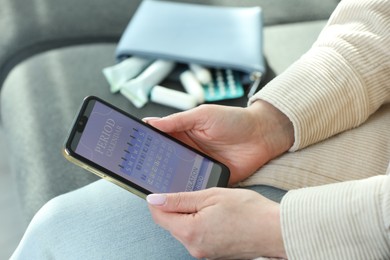 Photo of Menstruation. Woman using period calendar application on smartphone indoors, closeup