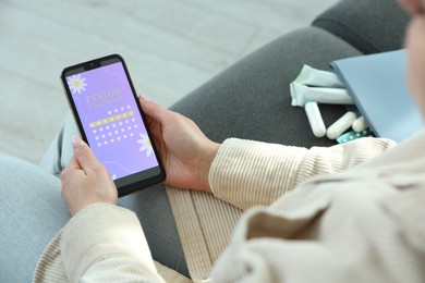 Photo of Menstruation. Woman using period calendar application on smartphone indoors, closeup