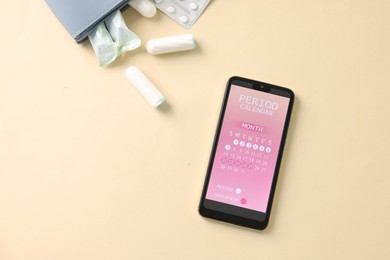 Photo of Smartphone with period calendar application and menstrual products on beige background, flat lay