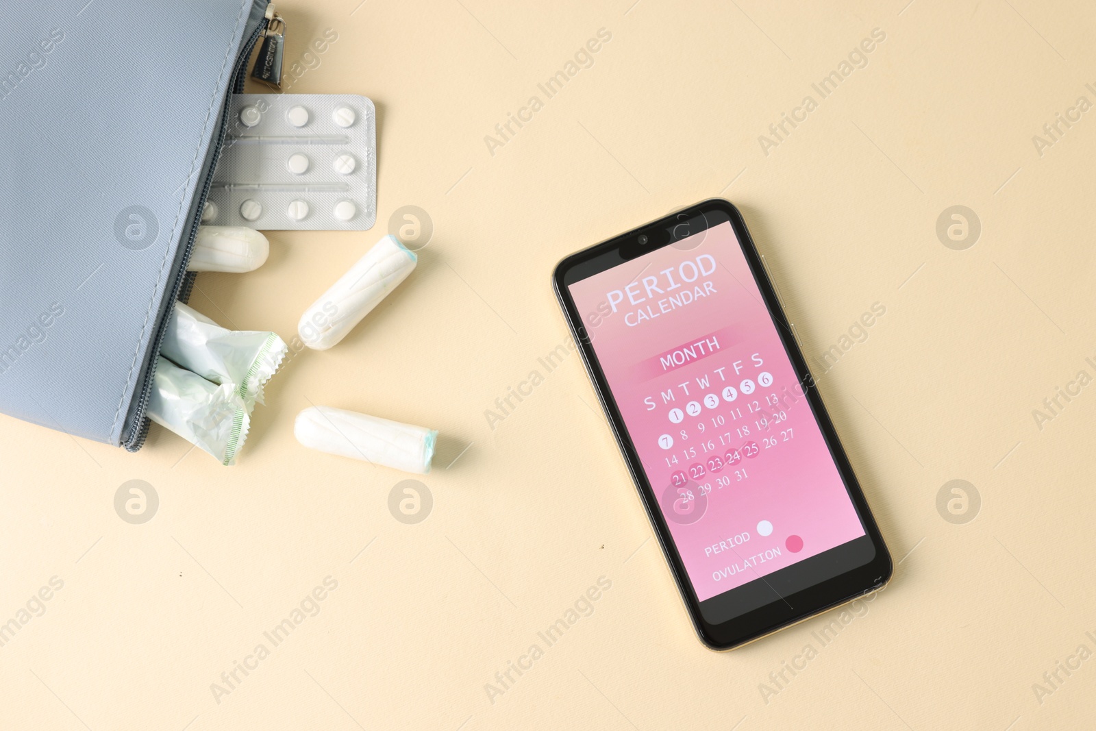 Photo of Smartphone with period calendar application and menstrual products on beige background, flat lay