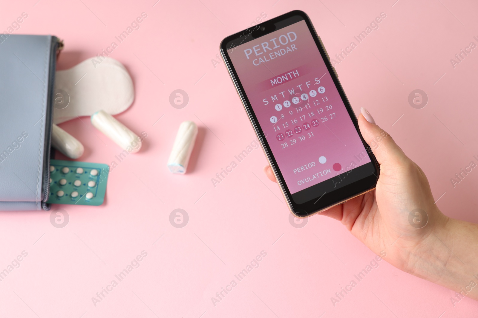 Photo of Menstruation. Woman holding smartphone with period calendar application on pink background, above view