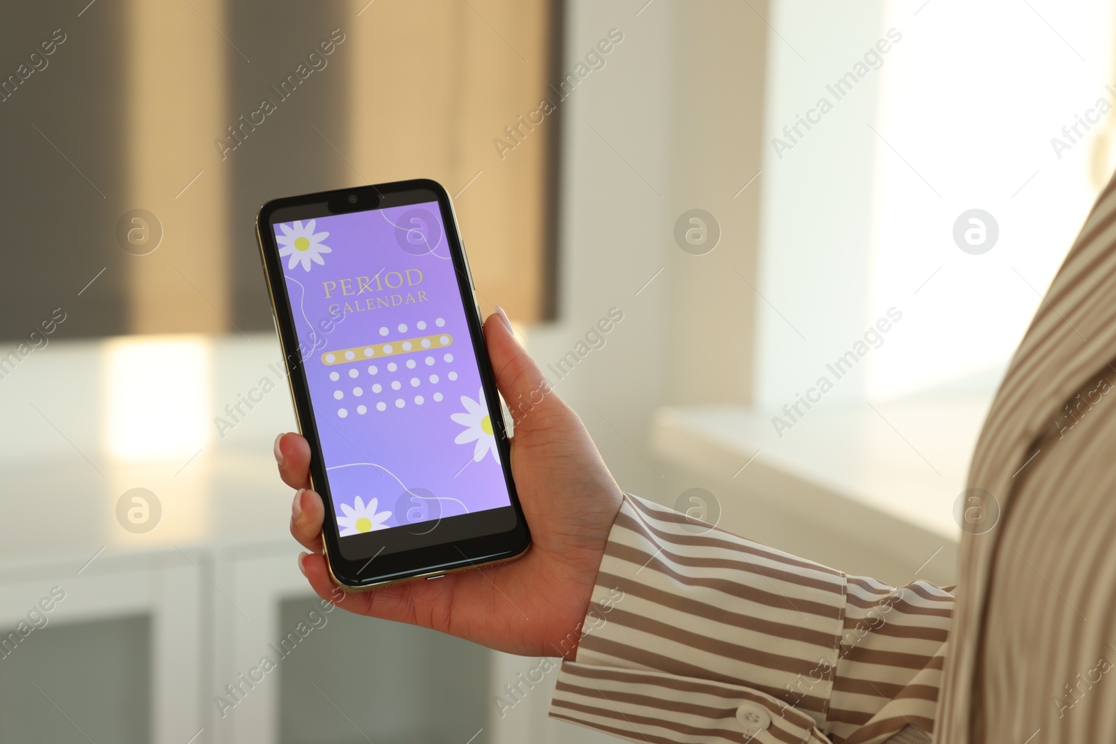 Photo of Menstruation. Woman using period calendar application on smartphone indoors, closeup