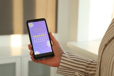 Photo of Menstruation. Woman using period calendar application on smartphone indoors, closeup