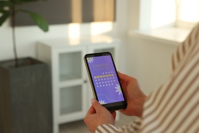 Photo of Menstruation. Woman using period calendar application on smartphone indoors, closeup. Space for text