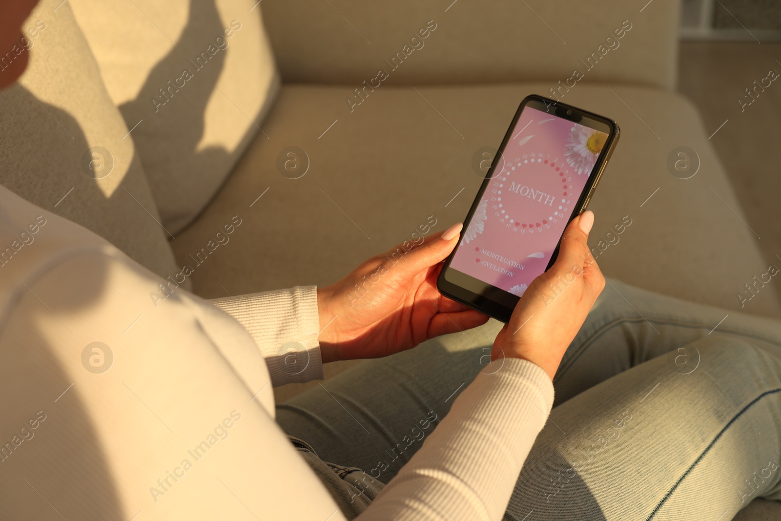 Photo of Menstruation. Woman using period calendar application on smartphone indoors, closeup