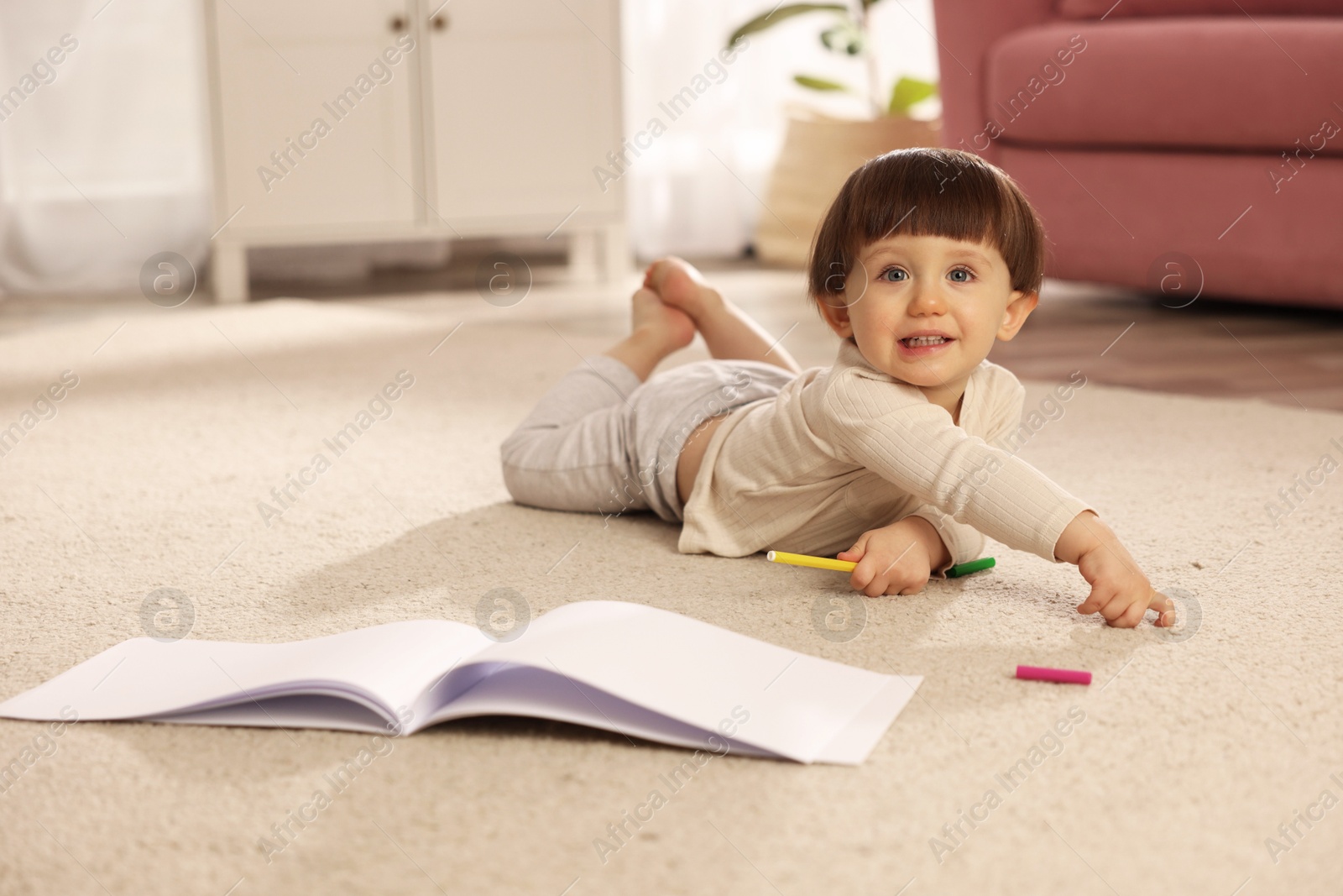 Photo of Cute little boy with felt pen and sketchbook on floor at home, space for text