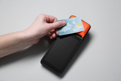 Photo of Woman with credit card using payment terminal on grey background, top view