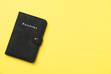 Photo of Passport in leather cover on yellow background, top view. Space for text