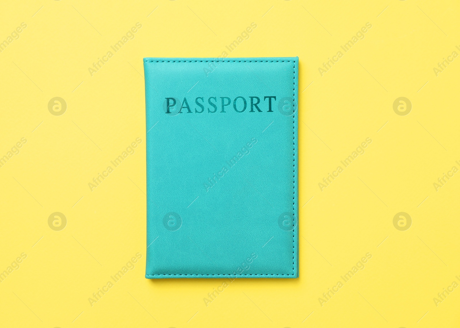 Photo of Passport in bright cover on yellow background, top view