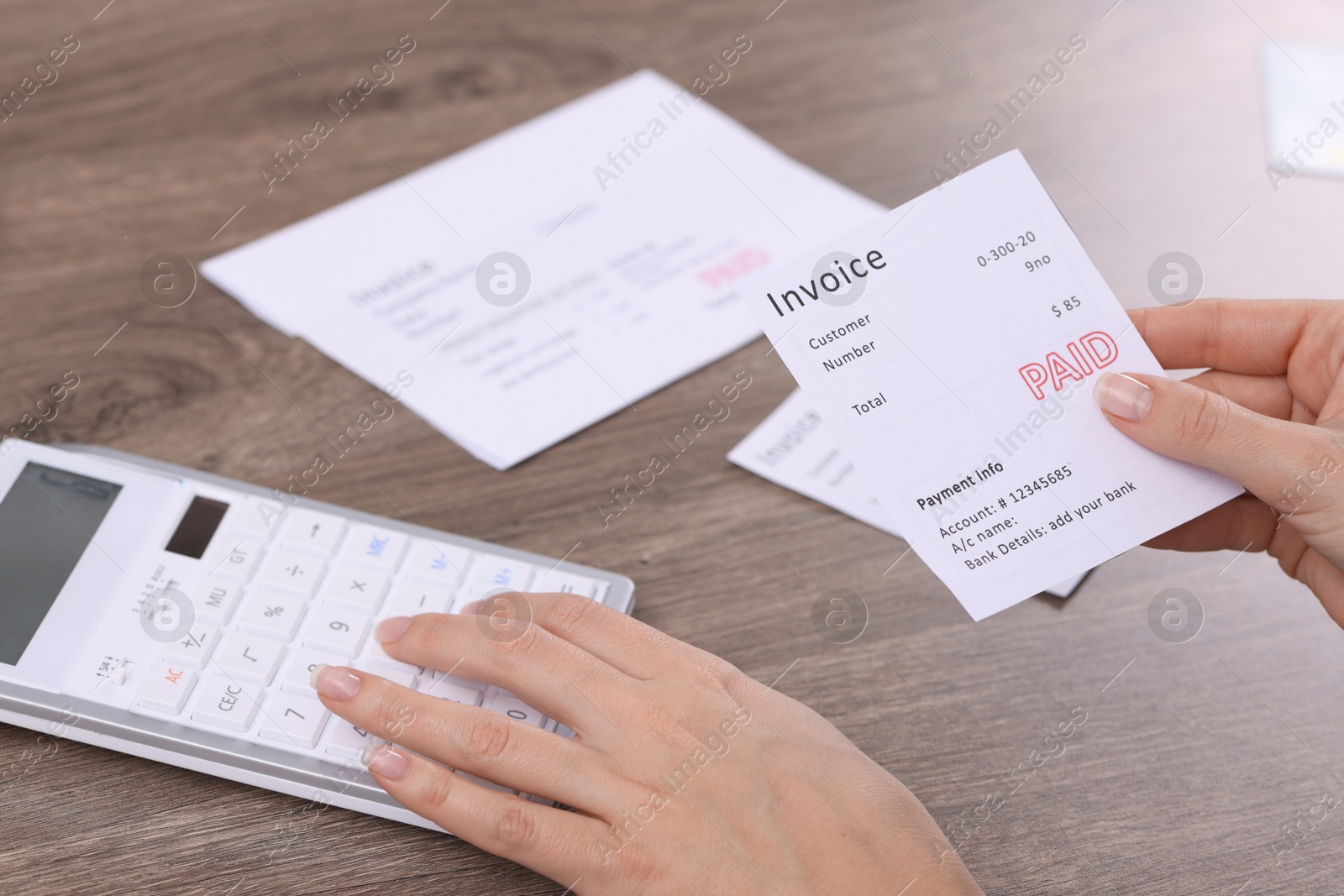 Photo of Paying bills. Woman with different invoices and calculator at wooden table indoors, closeup