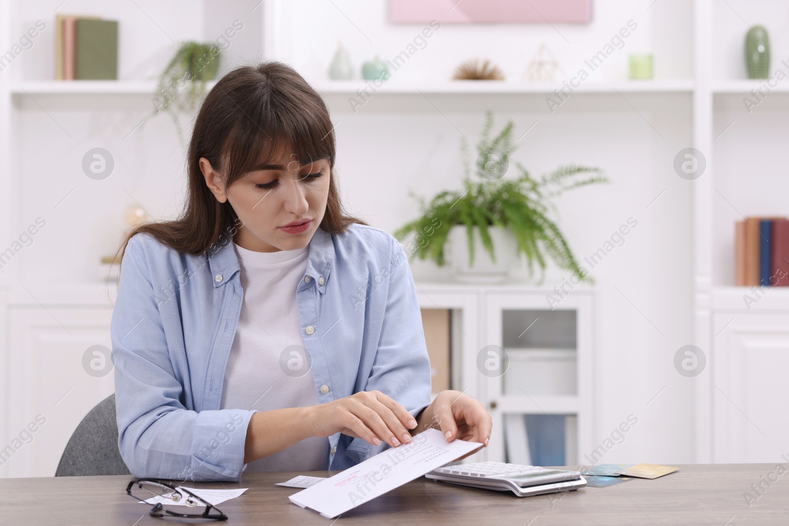 Photo of Paying bills. Woman with different invoices and calculator at wooden table indoors, space for text