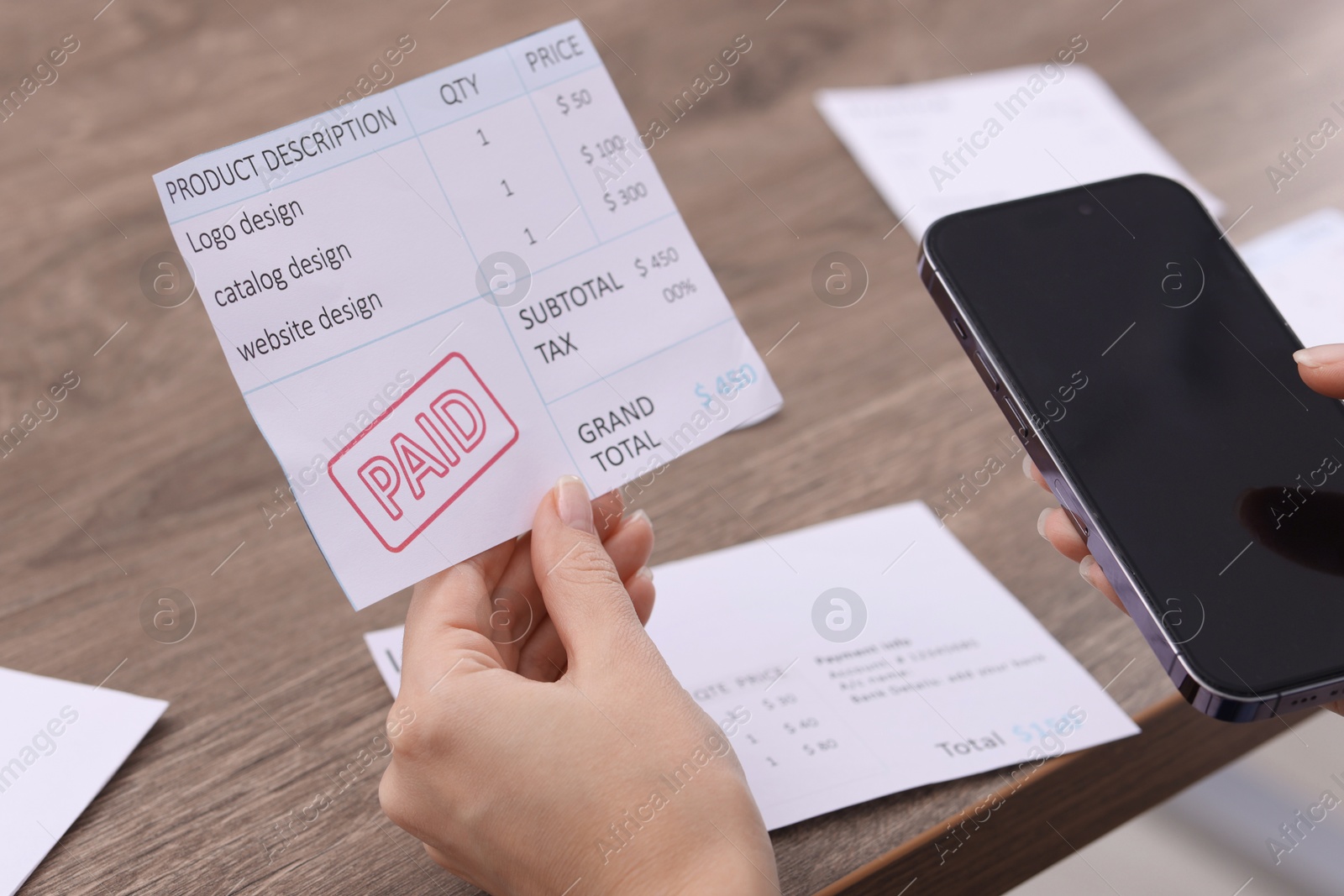 Photo of Paying bills. Woman with different invoices and phone at wooden table indoors, closeup