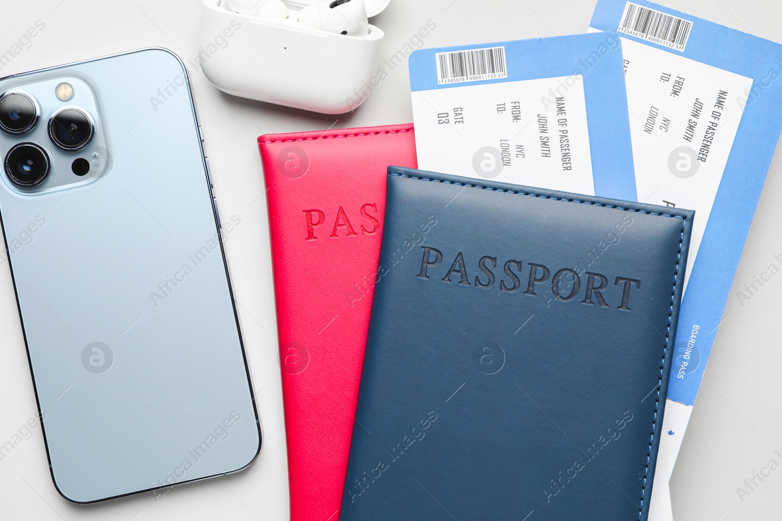 Photo of Travel agency. Flight tickets, passports and smartphone on grey background, flat lay