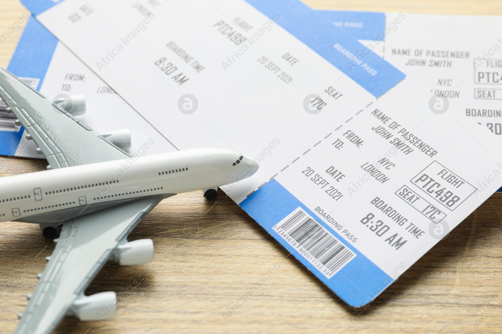 Photo of Travel agency. Flight tickets and plane model on wooden table, closeup