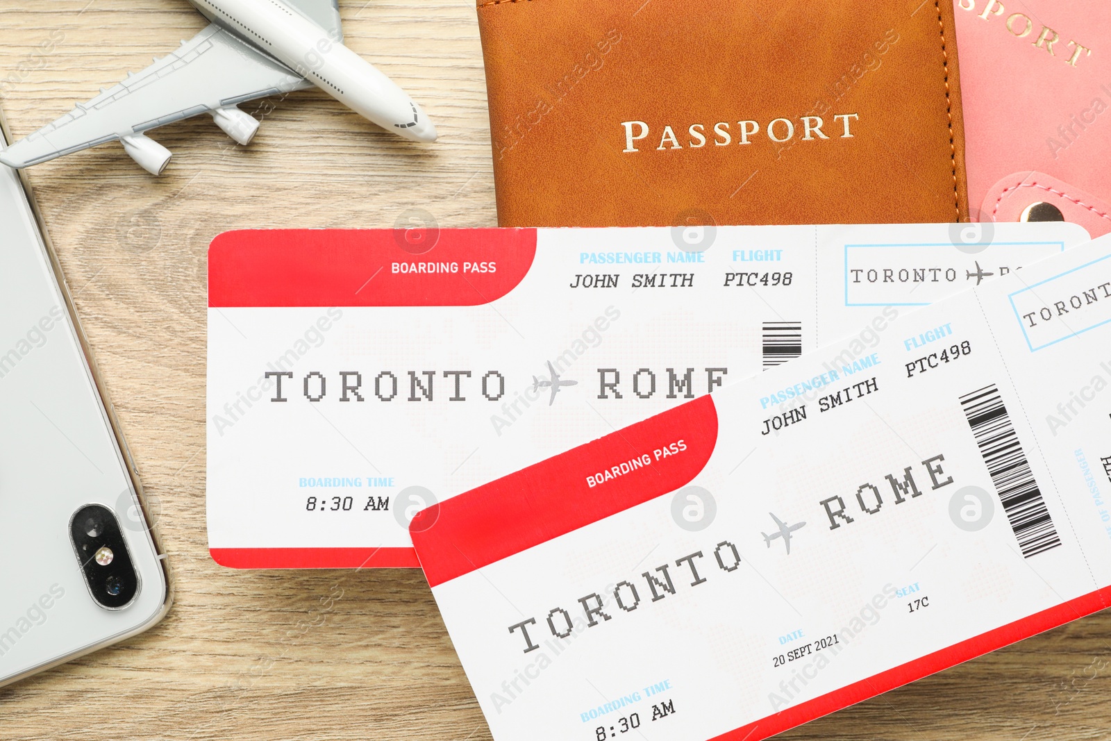 Photo of Travel agency. Flight tickets, passports, smartphone and plane model on wooden table, flat lay