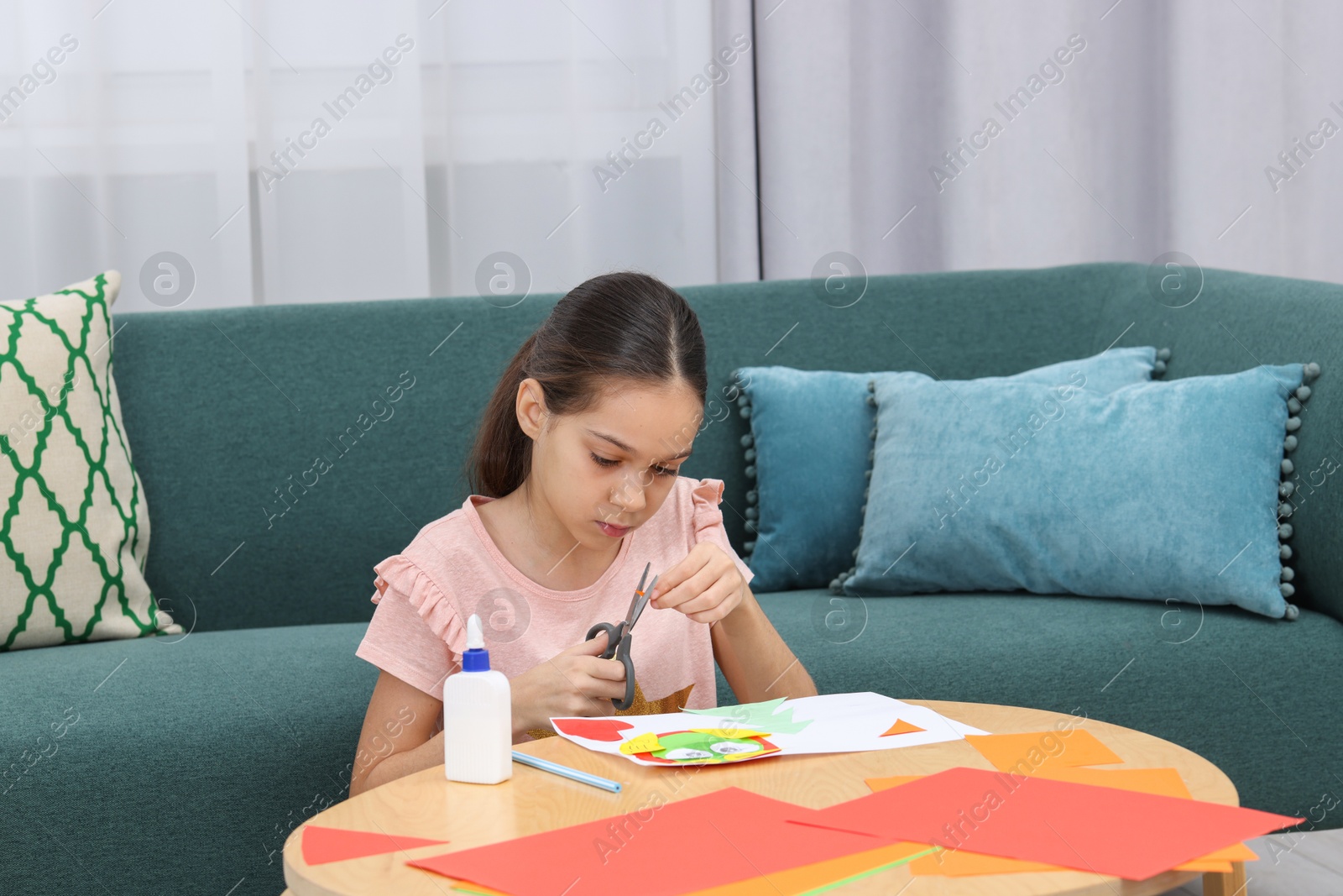 Photo of Girl cutting figure out of color paper for her creative project at home. Art and craft