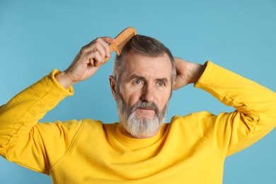 Photo of Handsome man combing his hair on light blue background