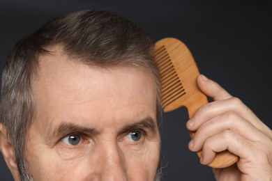 Photo of Man combing his hair on dark grey background, closeup