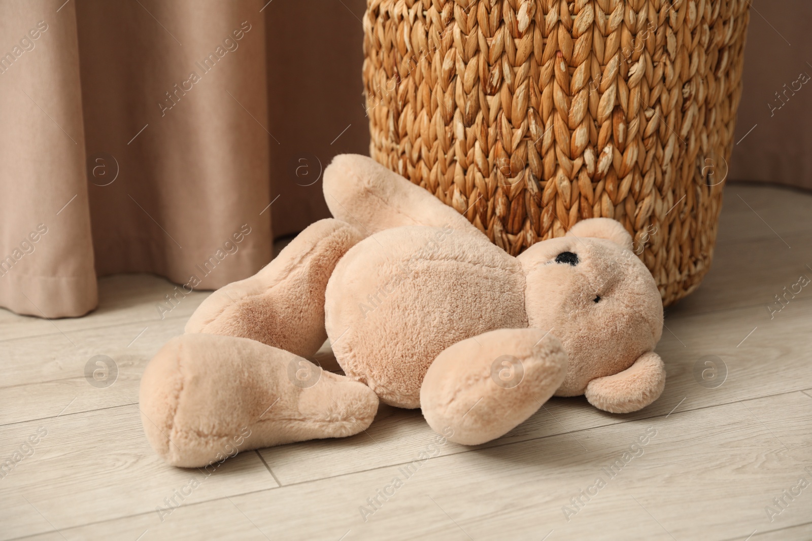 Photo of Teddy bear near basket on floor at home