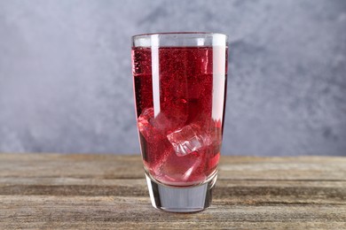 Photo of Sweet soda water with ice cubes in glass on wooden table