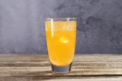 Photo of Sweet soda water with ice cubes in glass on wooden table