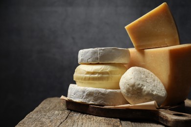 Photo of Different types of cheese on wooden table against grey background, closeup. Space for text