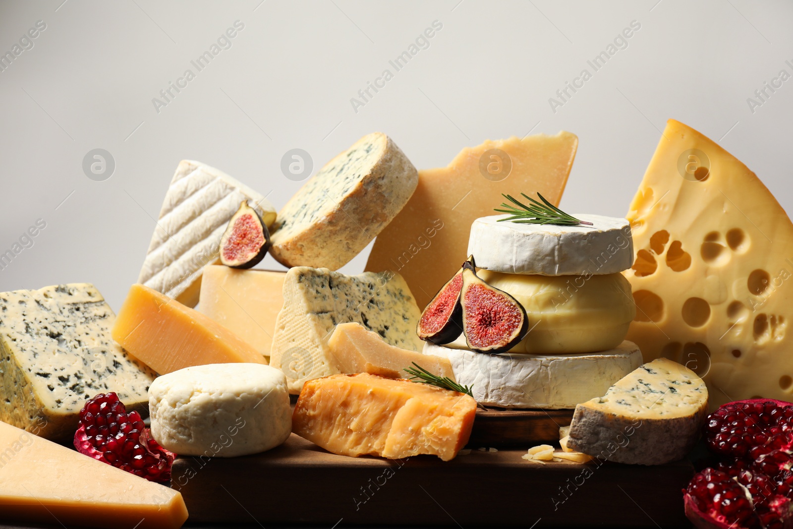 Photo of Different types of cheese, rosemary, figs and pomegranate on table