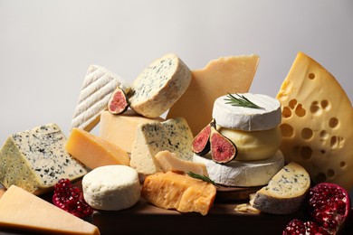 Photo of Different types of cheese, rosemary, figs and pomegranate on table