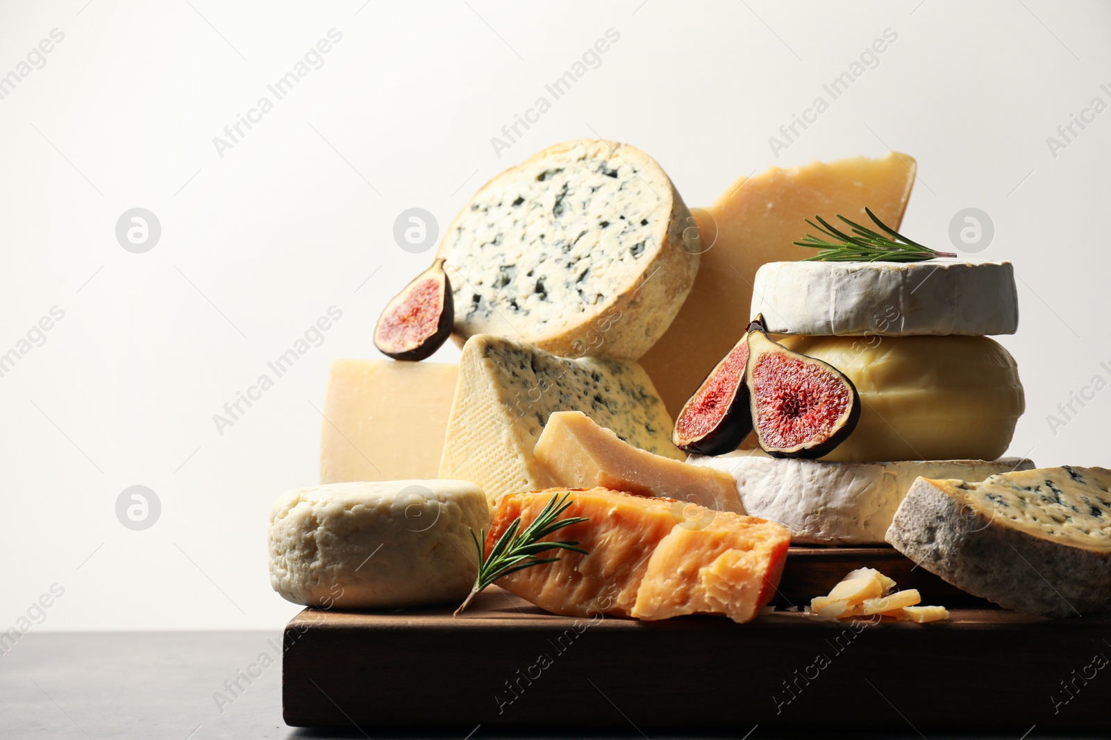 Photo of Different types of cheese, figs and rosemary on table, closeup. Space for text