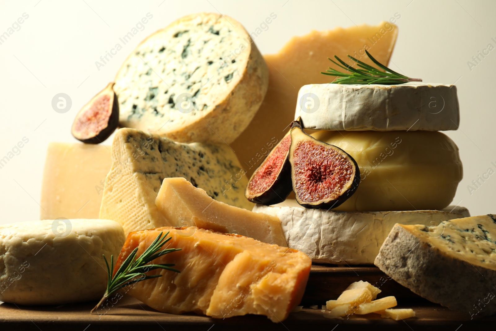 Photo of Different types of cheese, figs and rosemary on table, closeup