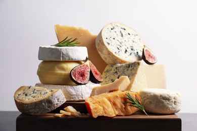 Photo of Different types of cheese, figs and rosemary on table, closeup