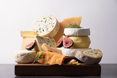 Photo of Different types of cheese, figs and rosemary on grey table