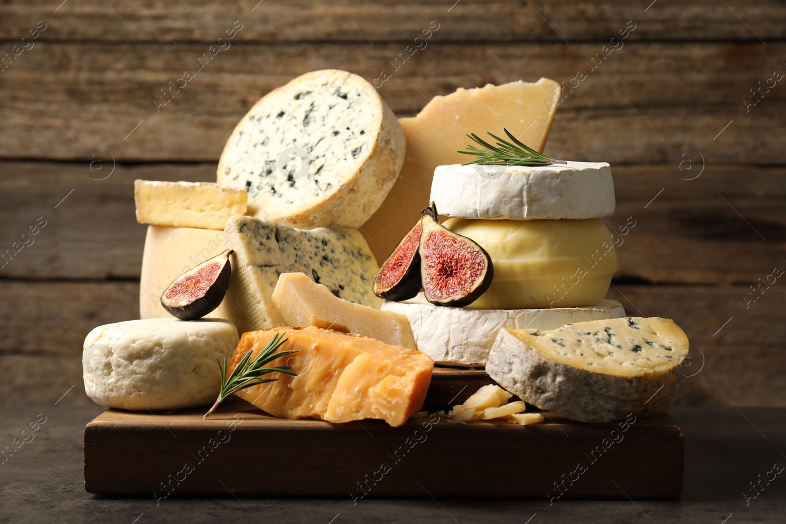 Photo of Different types of cheese, figs and rosemary on grey table