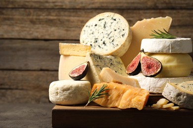 Photo of Different types of cheese, figs and rosemary on grey table, closeup. Space for text