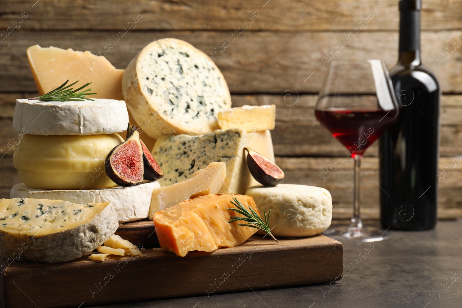 Photo of Different types of cheese, figs, rosemary and wine on grey table, closeup