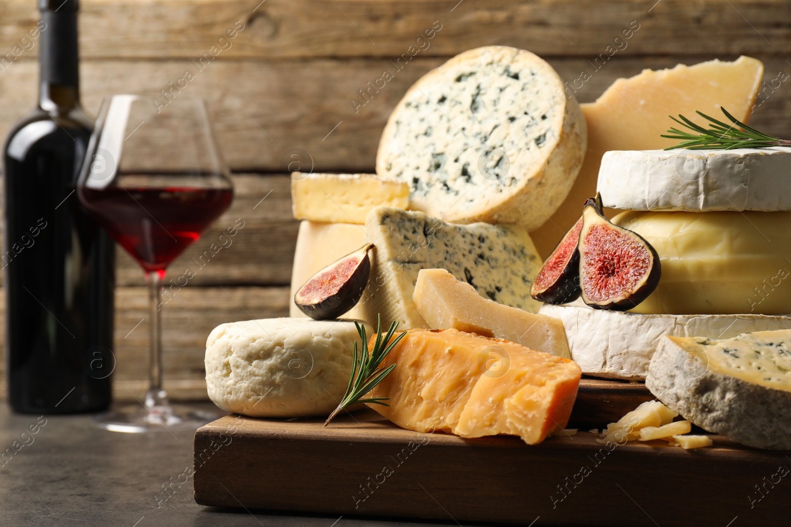 Photo of Different types of cheese, figs, rosemary and wine on grey table, closeup