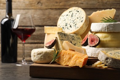 Photo of Different types of cheese, figs, rosemary and wine on grey table, closeup