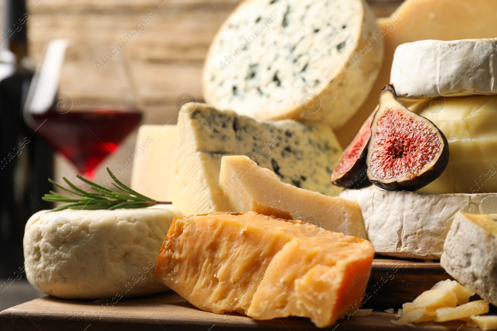 Photo of Different types of cheese, figs and rosemary on table, closeup